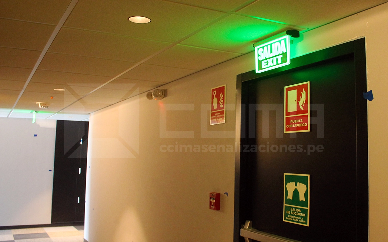 expertos instalando señales vías de evacuación normativa peruana en un edificio corporativo de Lima